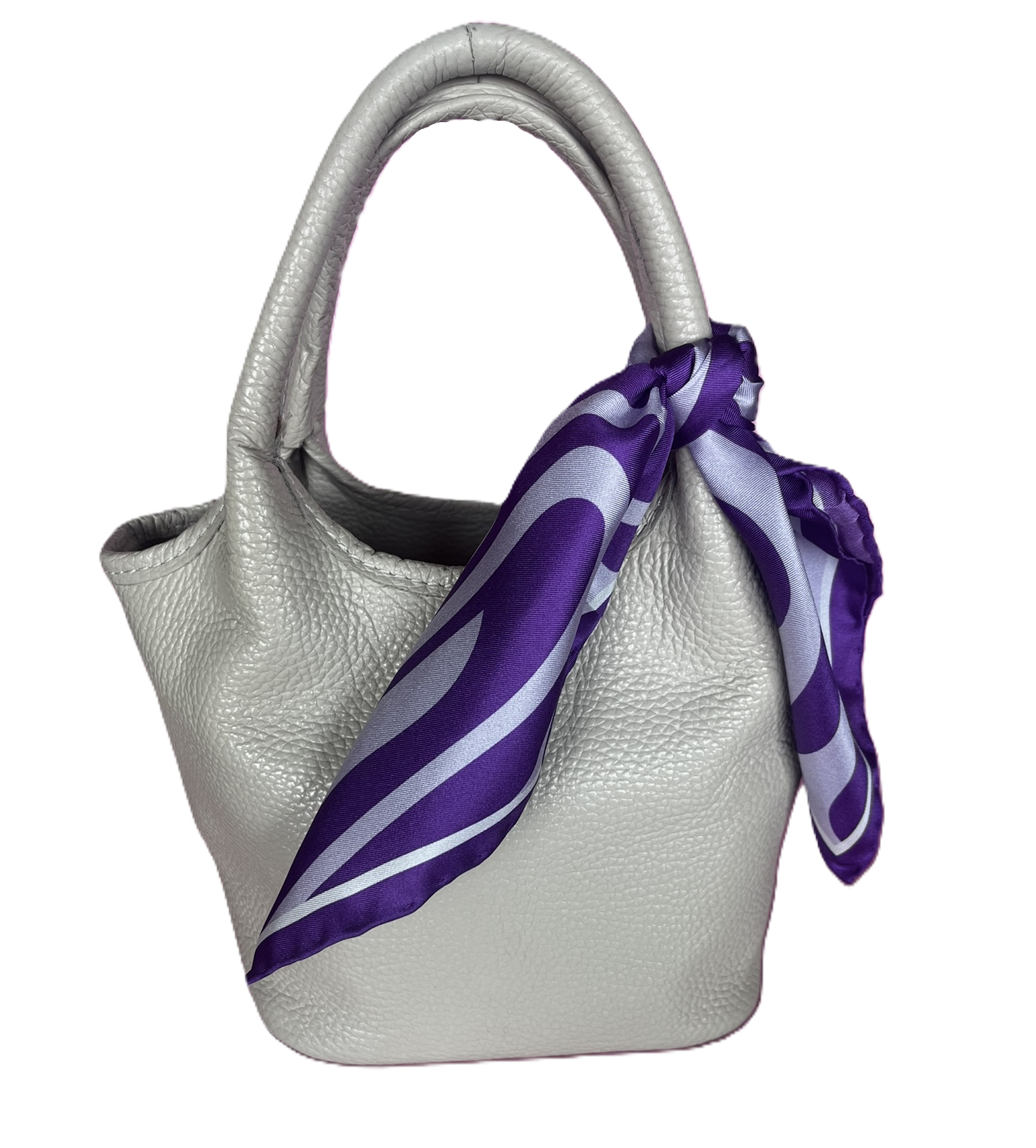 A white textured leather handbag with a apashka Acid Wave silk scarf tied around its handle.