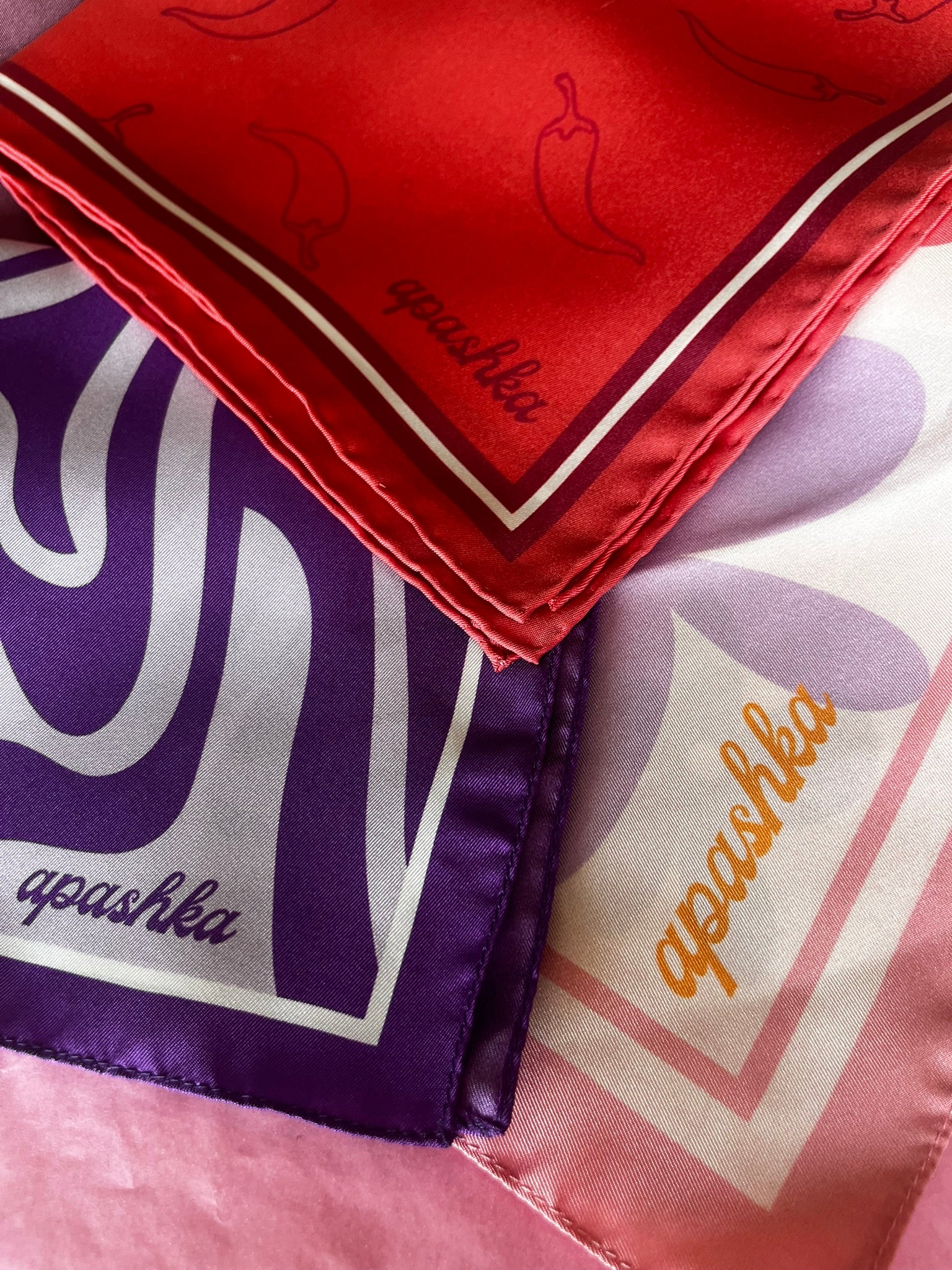 Three scarves with 'apushka' branding in different colors and patterns.