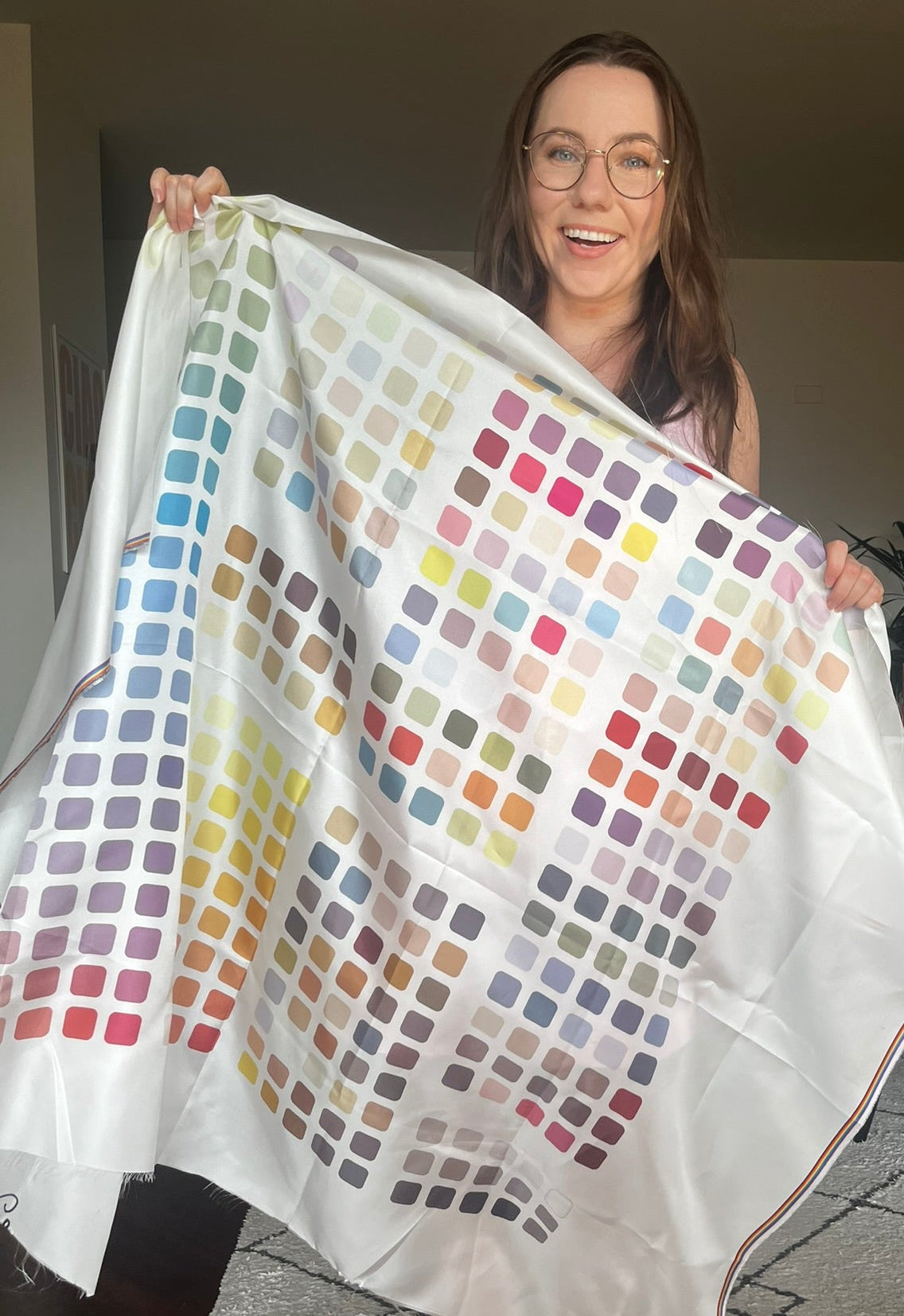 Woman holding a big colorful square patterned fabric with colour swatches
