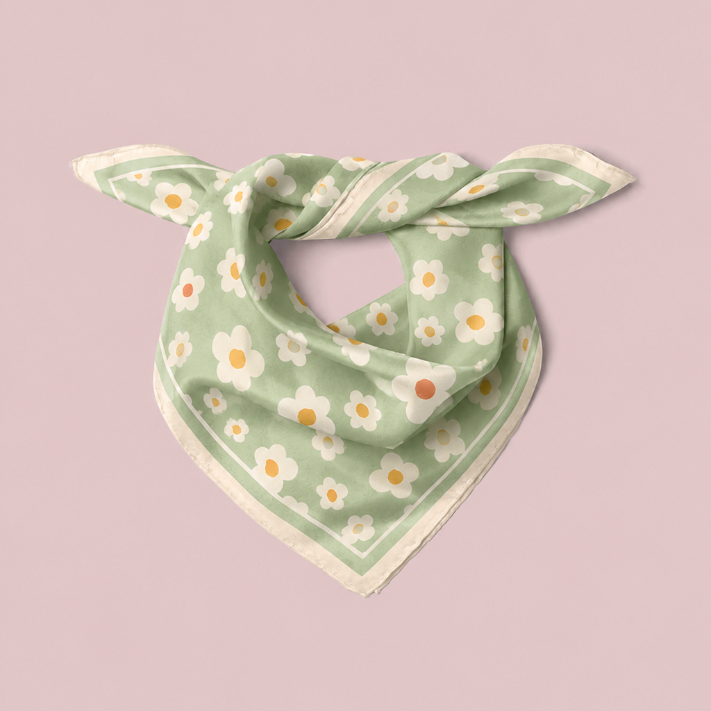 apashka Daisy Daze square silk scarf folded and knotted into a neckerchief style, featuring a retro white and yellow daisy floral pattern on a sage green background, isolated against a soft pink backdrop.
