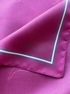 Close up of the signature apashka script logo on the corner of the silk bandana in dark magenta colour.