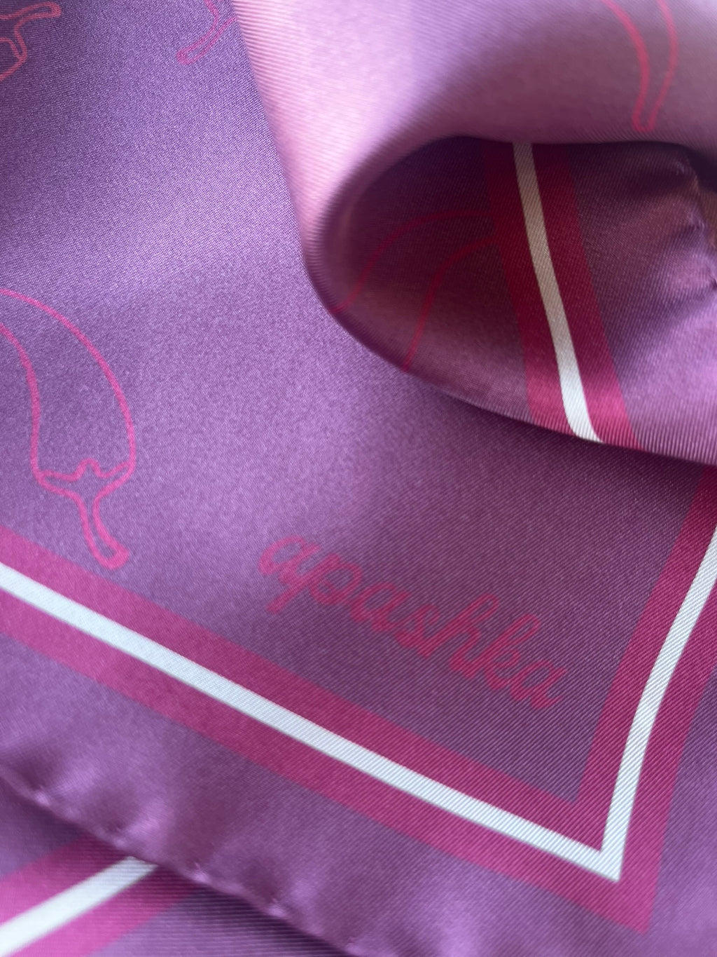 Close up of the signature apashka script logo on the corner of the Red Hot Chili Apashka in purple plum colour.
