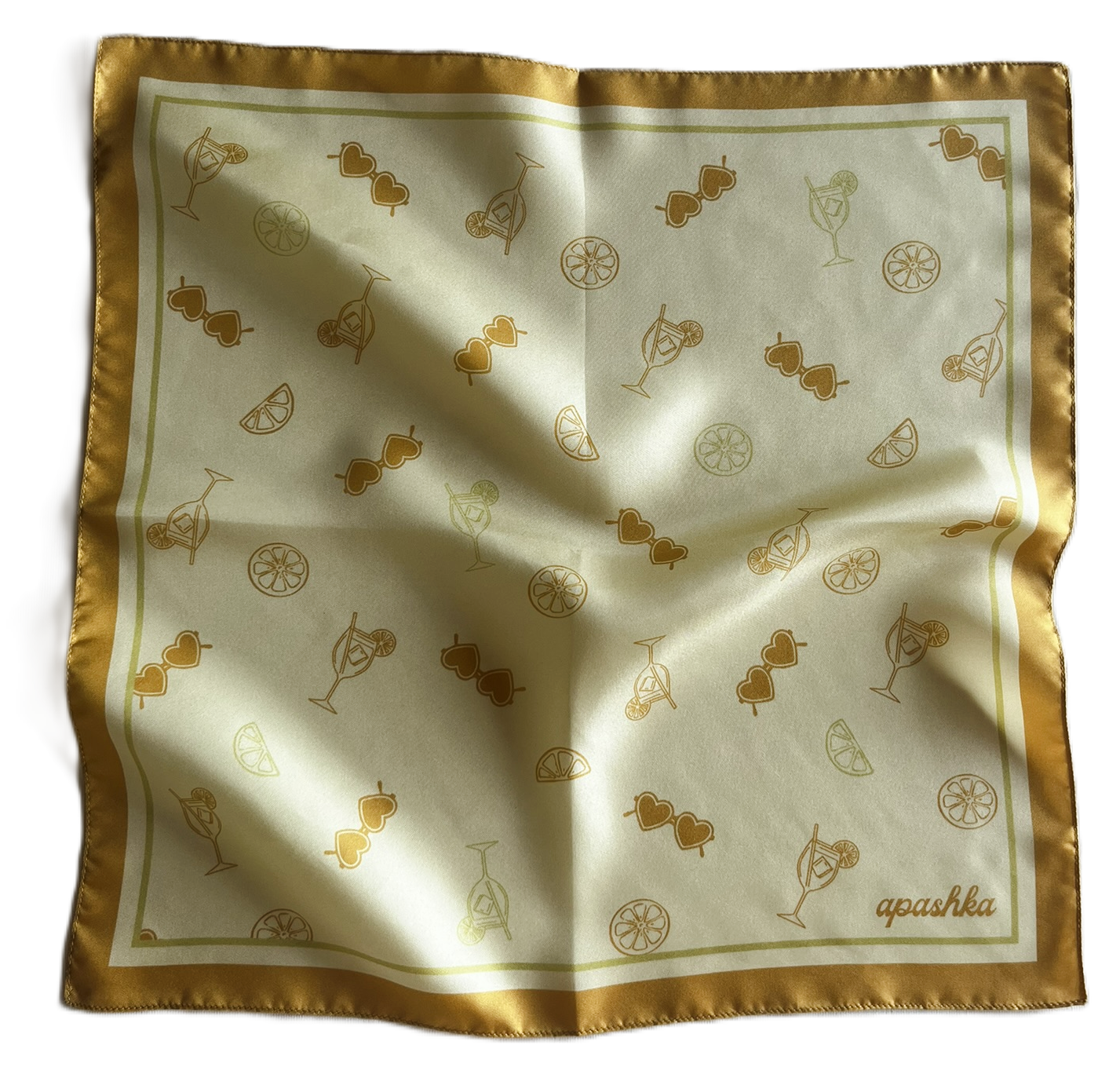 A top-down view of a square silk scarf slightly rippled and draped. The scarf has a warm cream-colored center scattered with an all-over gold orange art pattern of cocktails, lemon slices, and heart sunglasses, framed by a thick golden-yellow border.